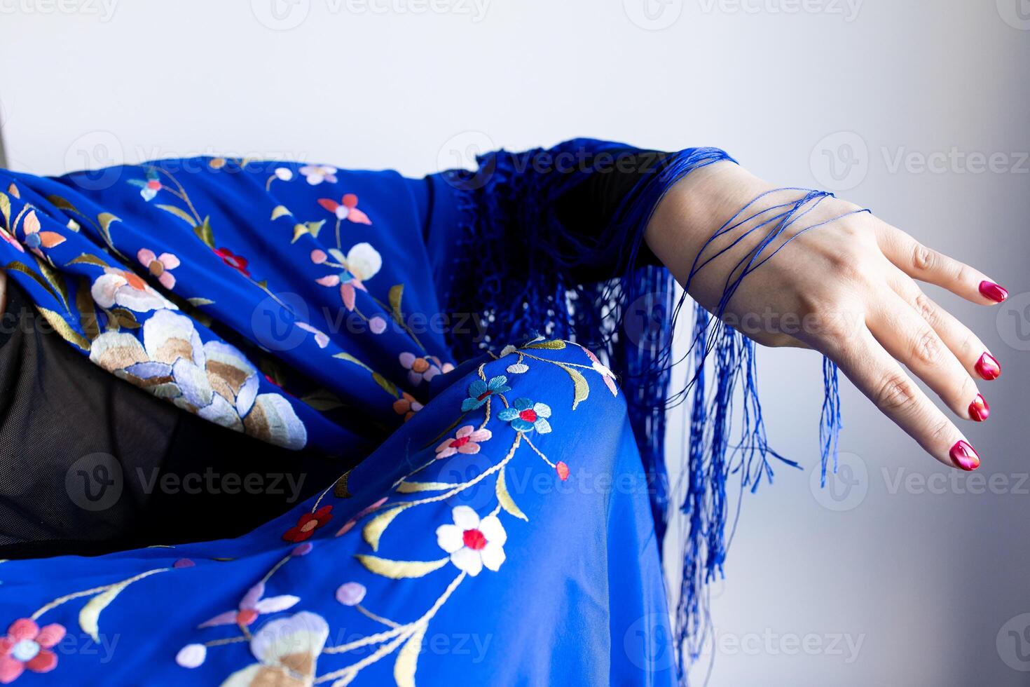 Elegant female arm in floral blue shawl with fringe details photo
