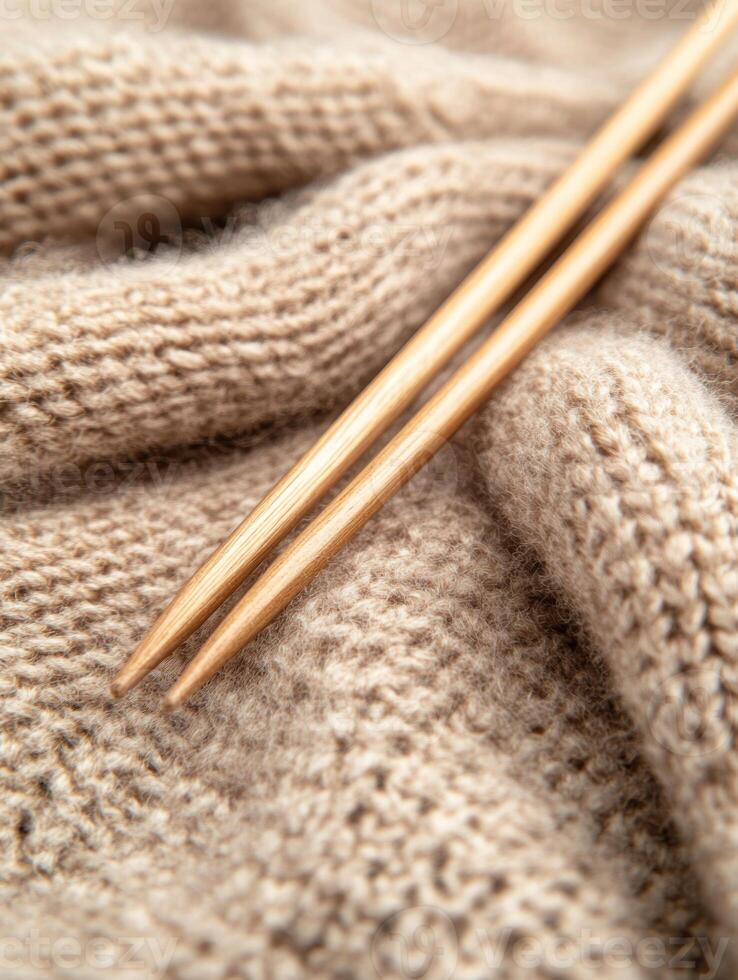 Cozy beige woolen fabric with knitting needles. Perfect for warm winter projects photo