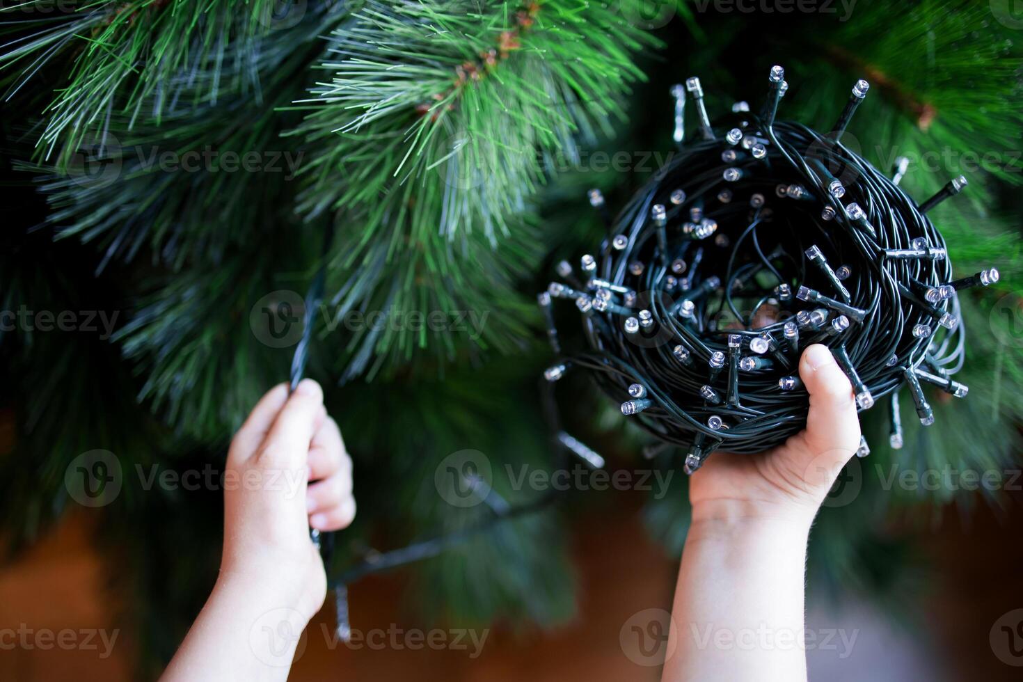 Child preparing Christmas tree with string lights photo
