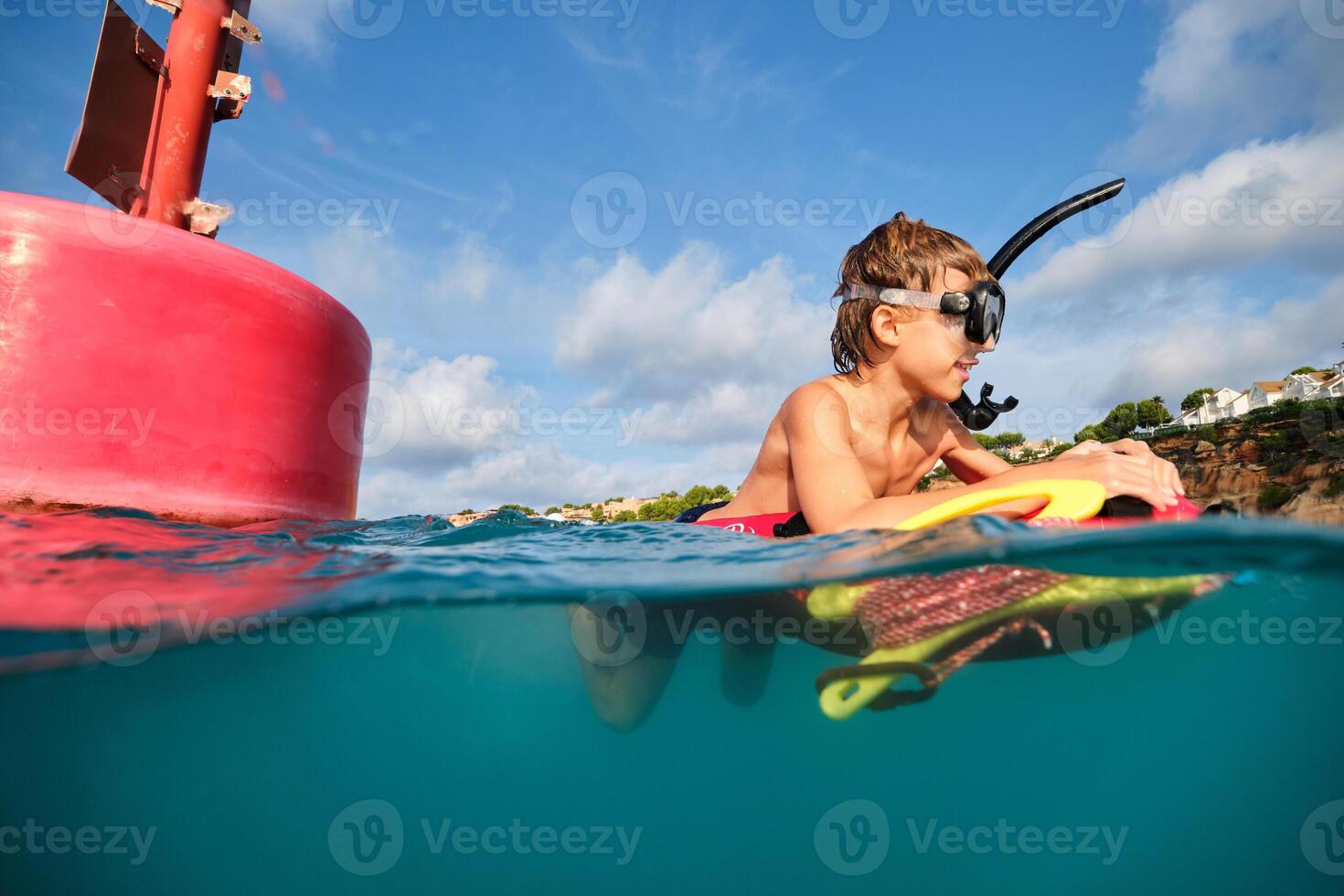 Happy kid in diving mask in seawater near red buoy photo