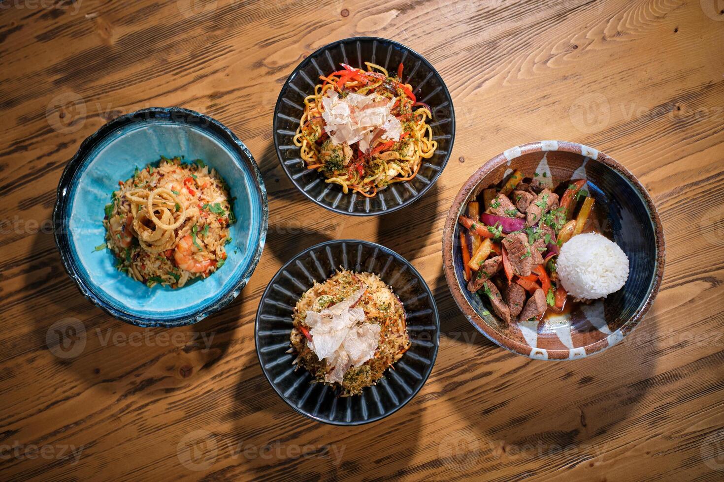 Four bowls of food on a wooden table. photo