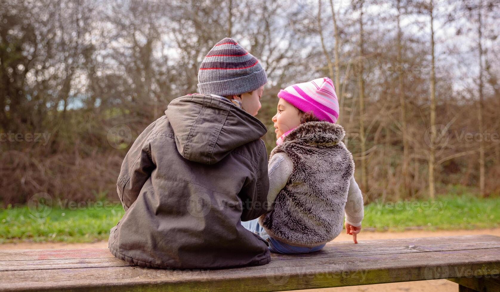 Two children sitting on a bench in the park. photo