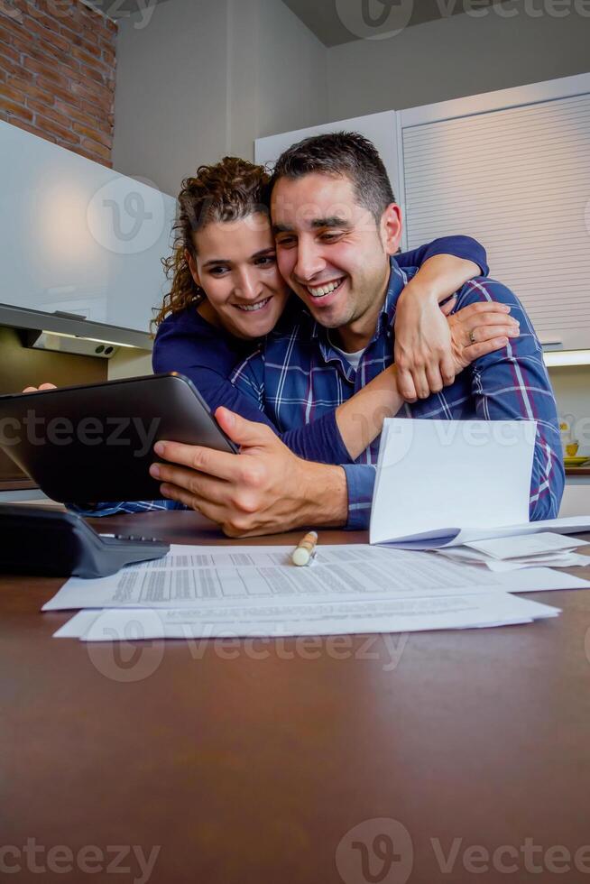 A man and woman are smiling while looking at a tablet photo