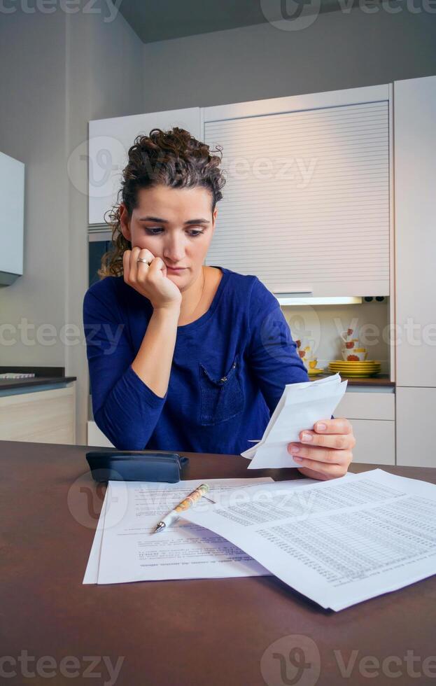 A woman is sitting at a table with a calculator and papers photo