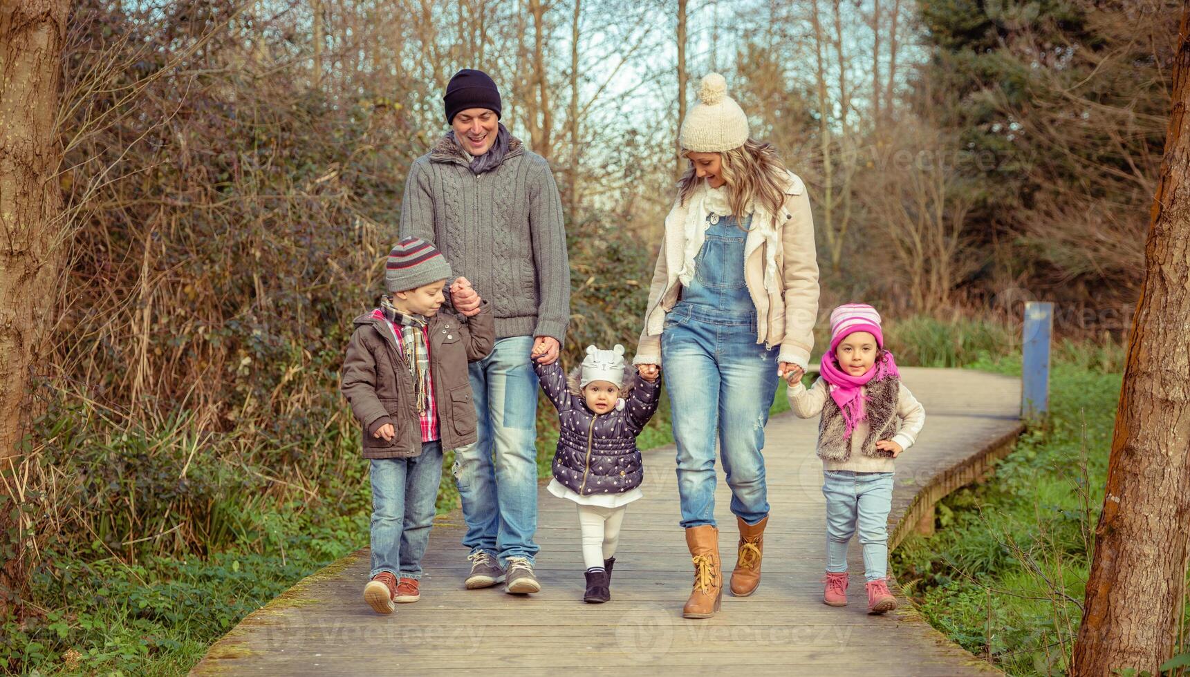 A happy family walking on a wooden path in the woods together photo
