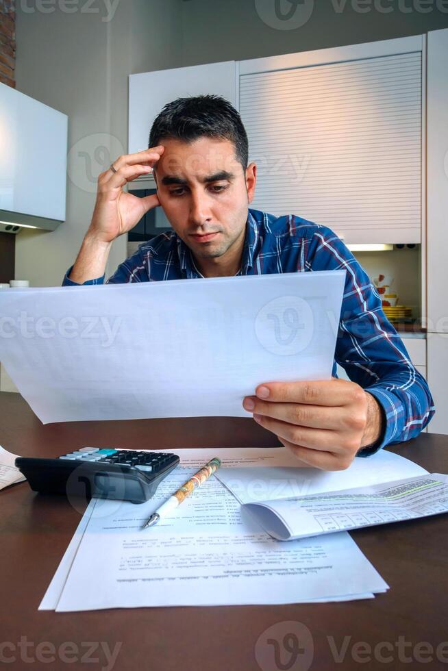 Man with papers and calculator at home photo