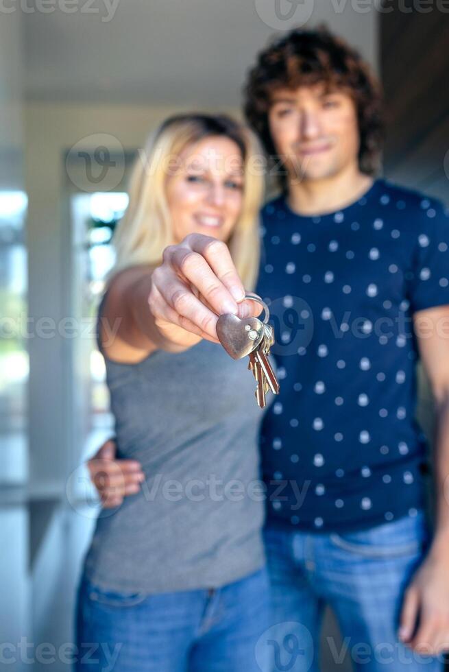 A man and woman holding keys in front of a house. photo
