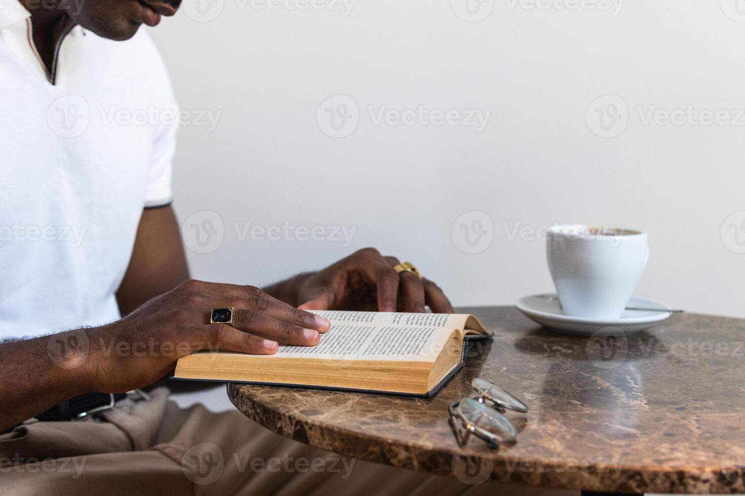 A man is reading a book while sitting at a table. photo