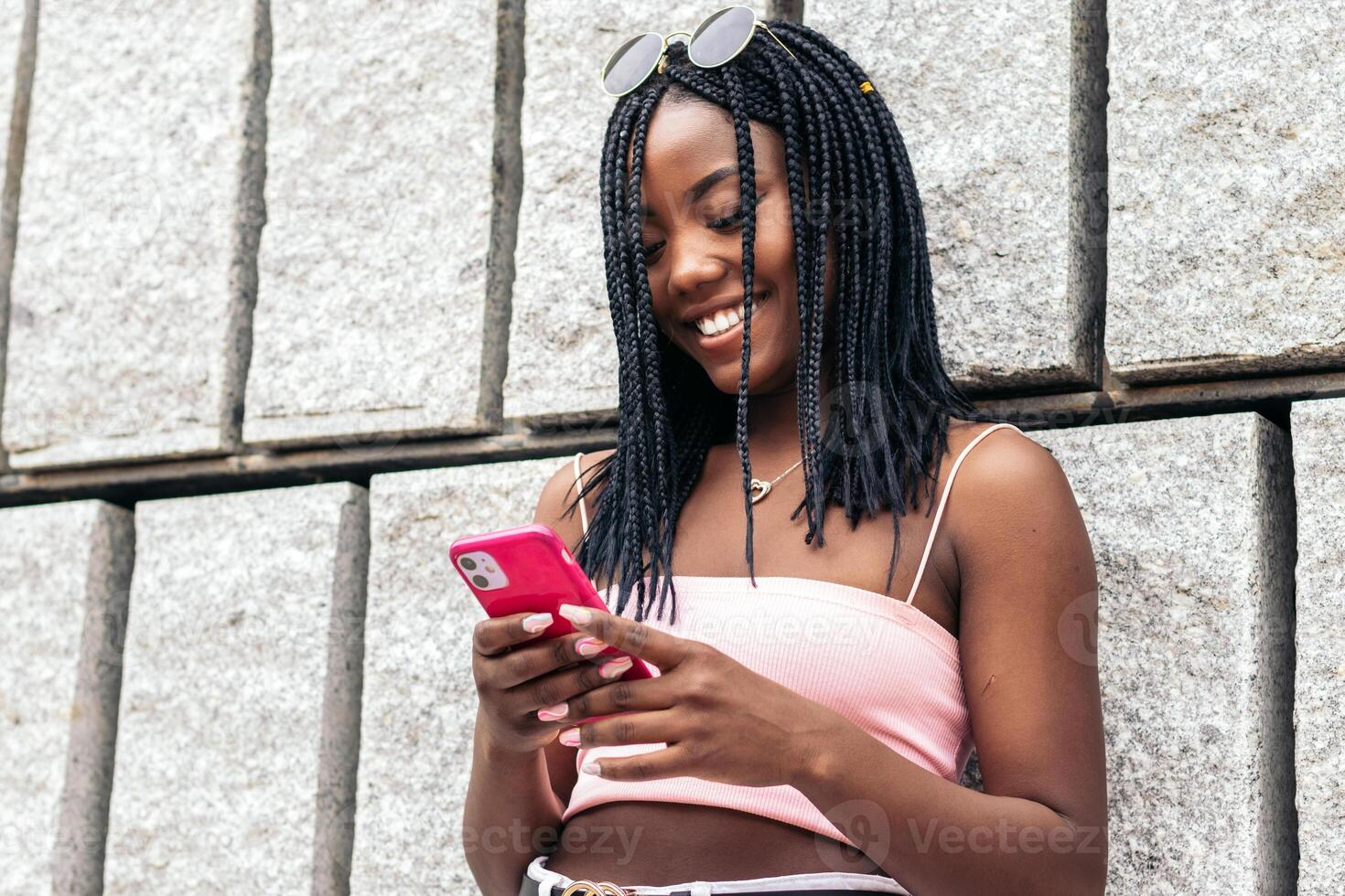 A woman with dreadlocks is smiling while using her phone photo