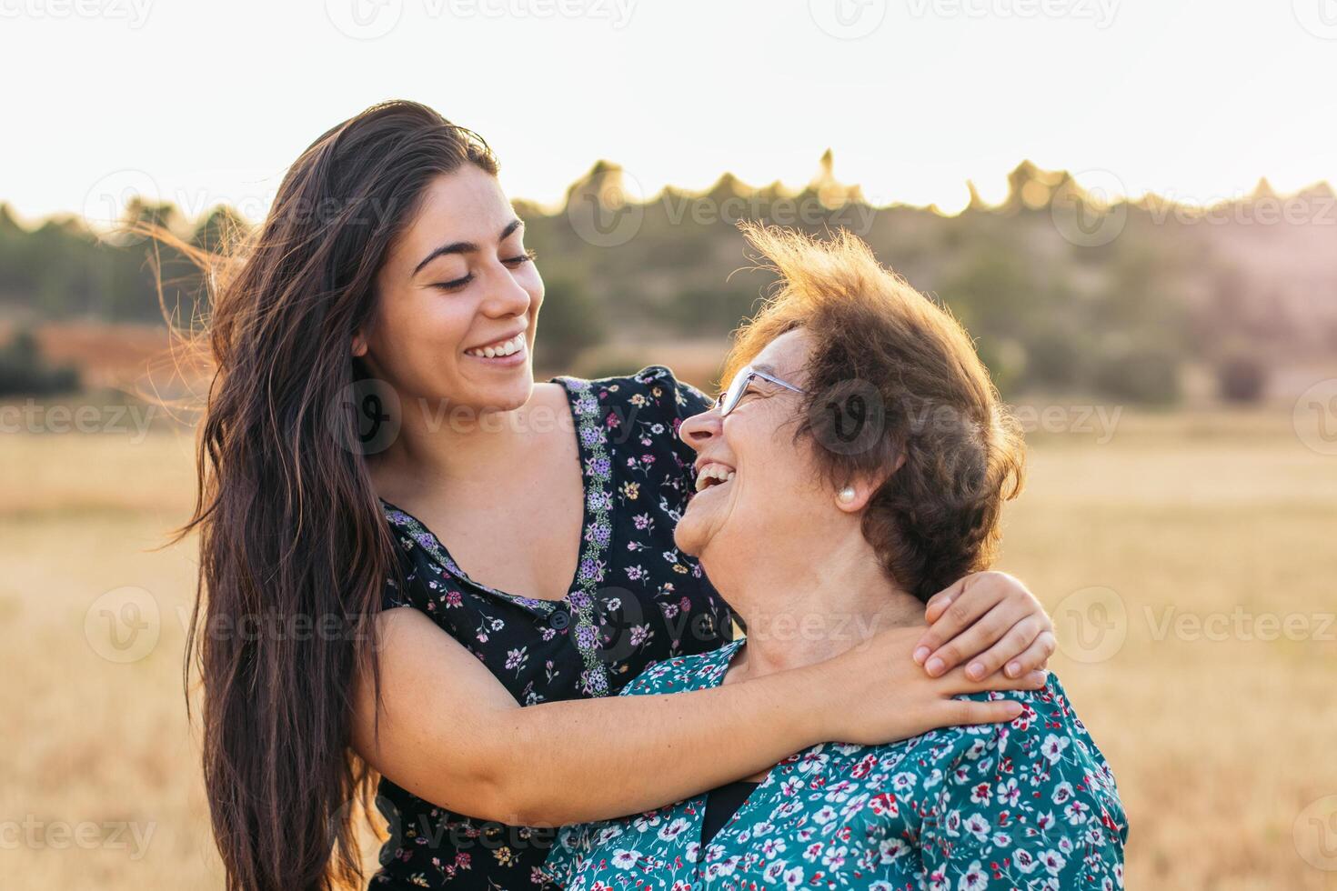A woman hugging her grandmother in a field. photo