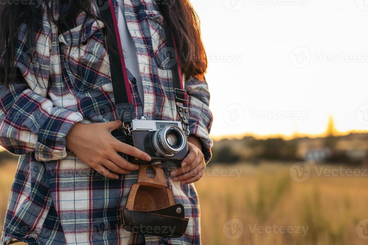 A woman holding a camera in a field photo