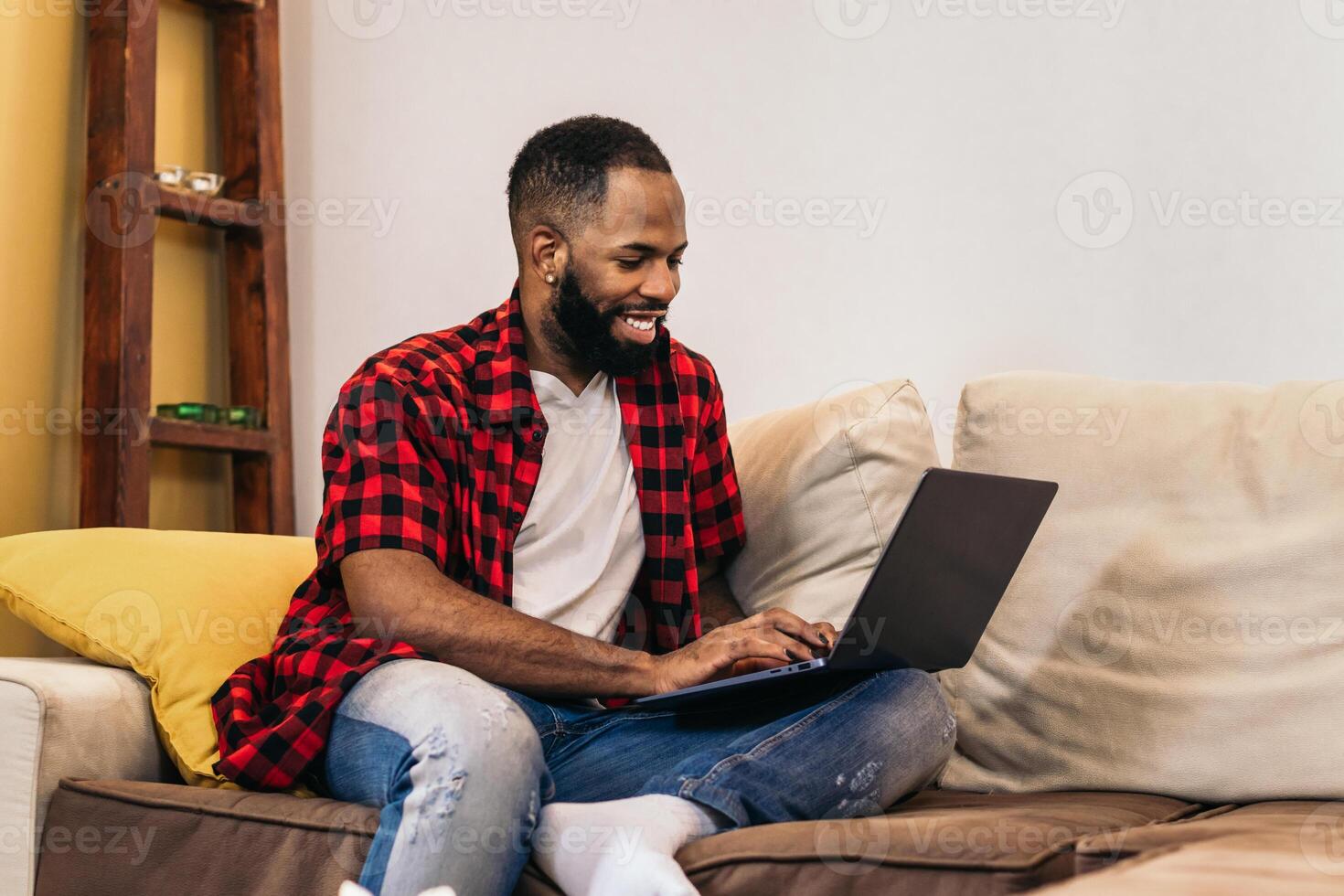 A man sitting on a couch with a laptop on his lap photo