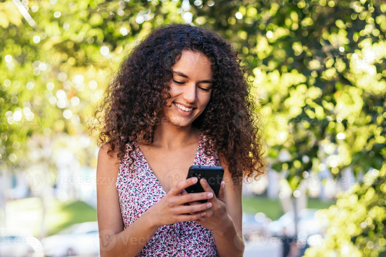 African-American girl using a smartphone in the park on a summer day. photo