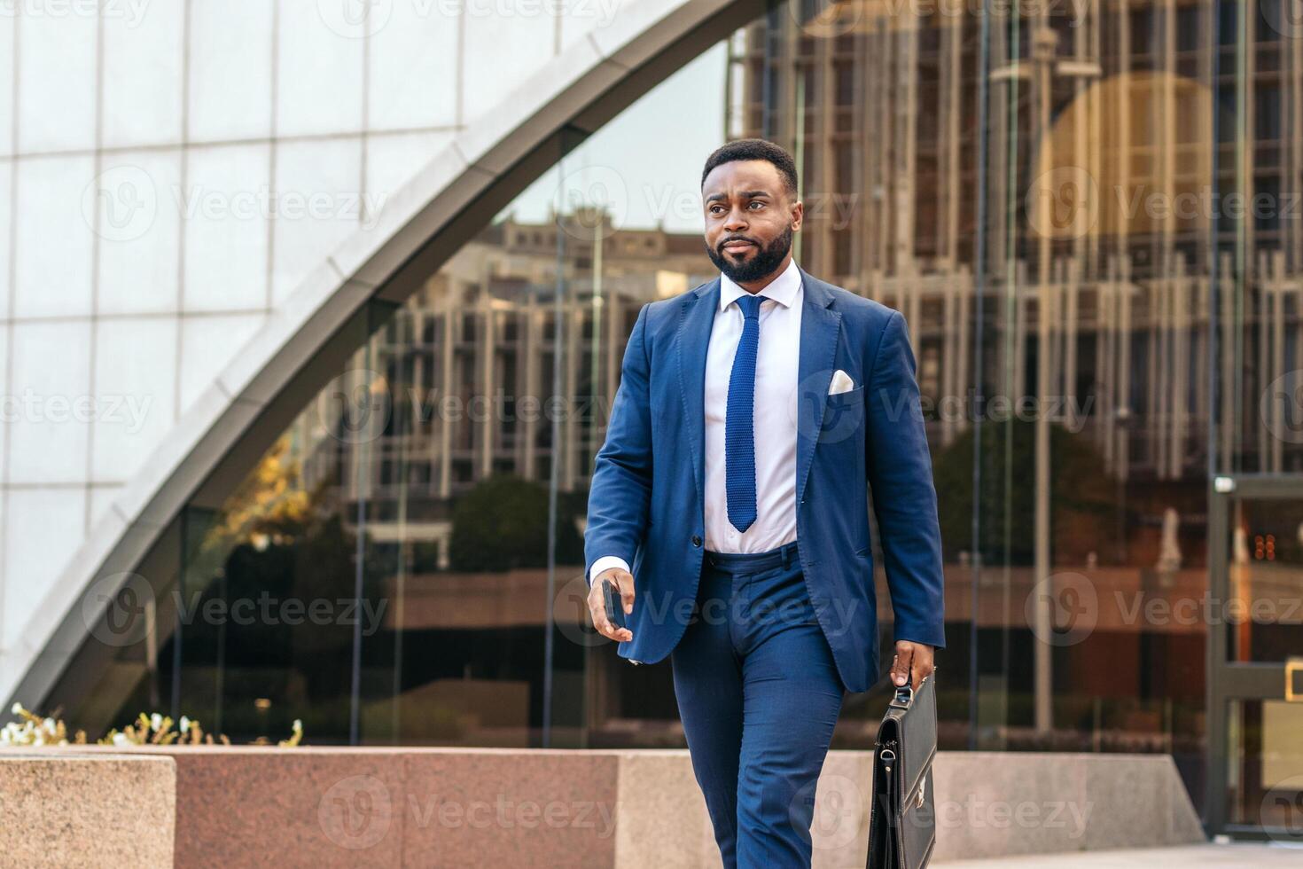 A man in a suit and tie with a suitcase in hand walking down the street photo