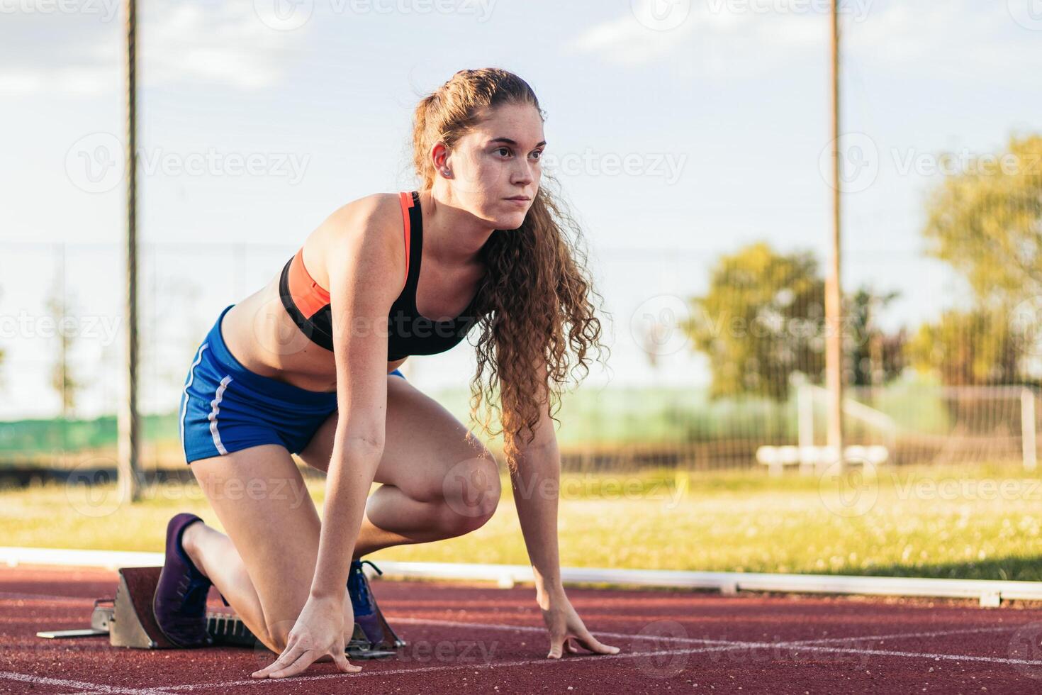 A young woman is kneeling on the track photo
