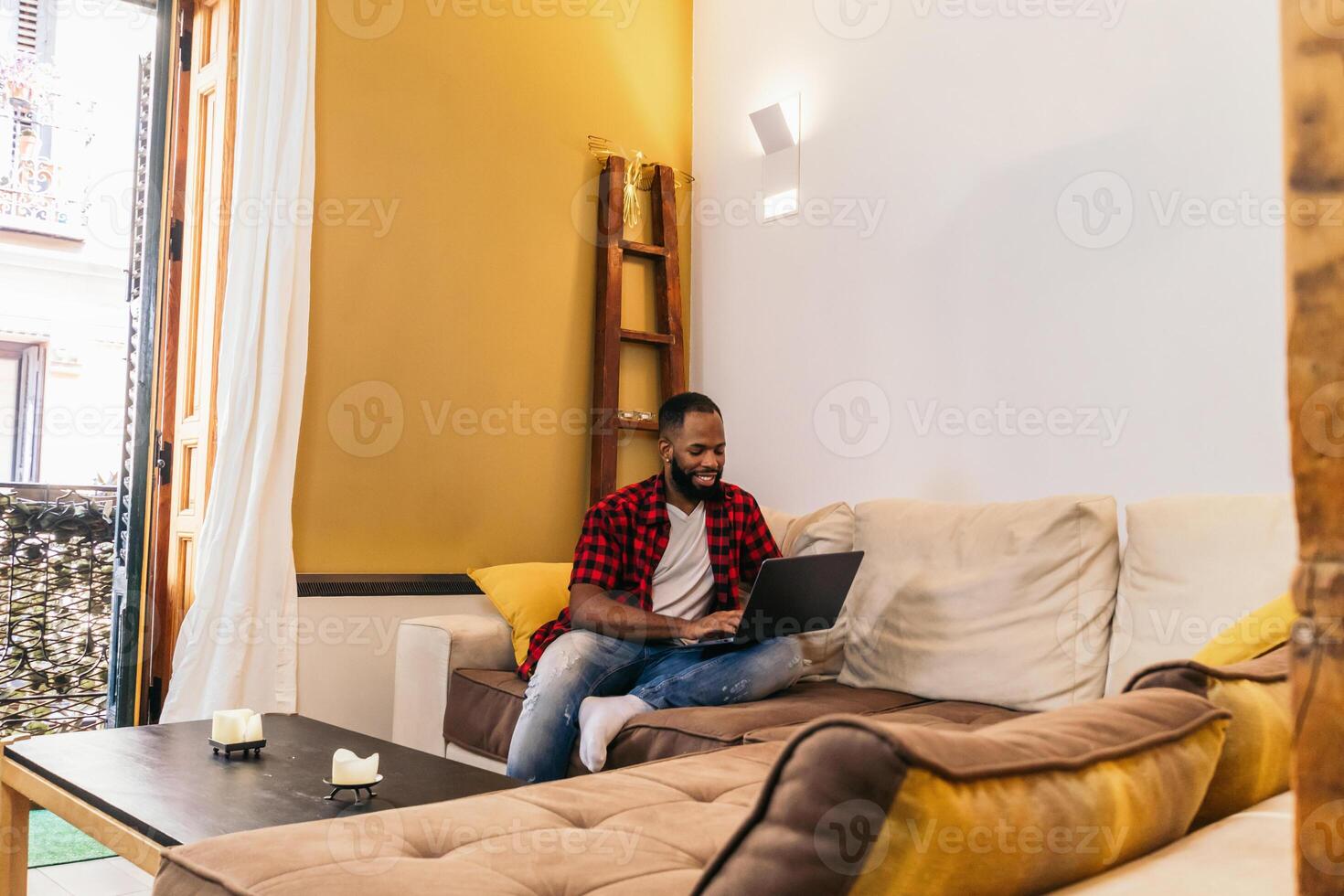 A man sitting on a couch with a laptop on his lap. photo