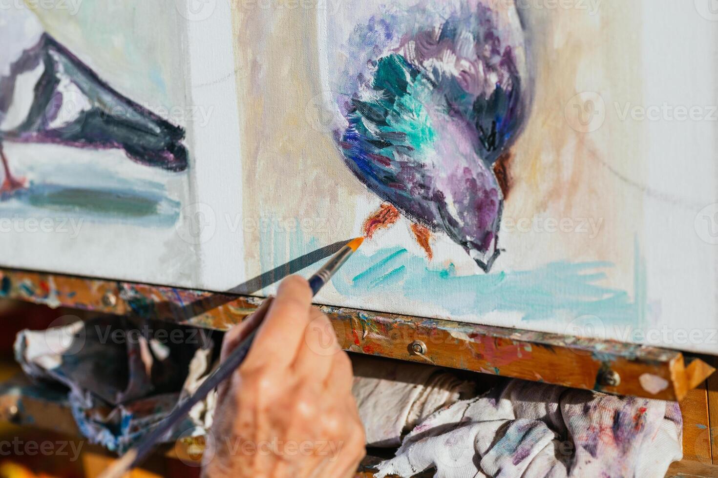 A person is painting a bird on a canvas. A painter is using a paint brush photo