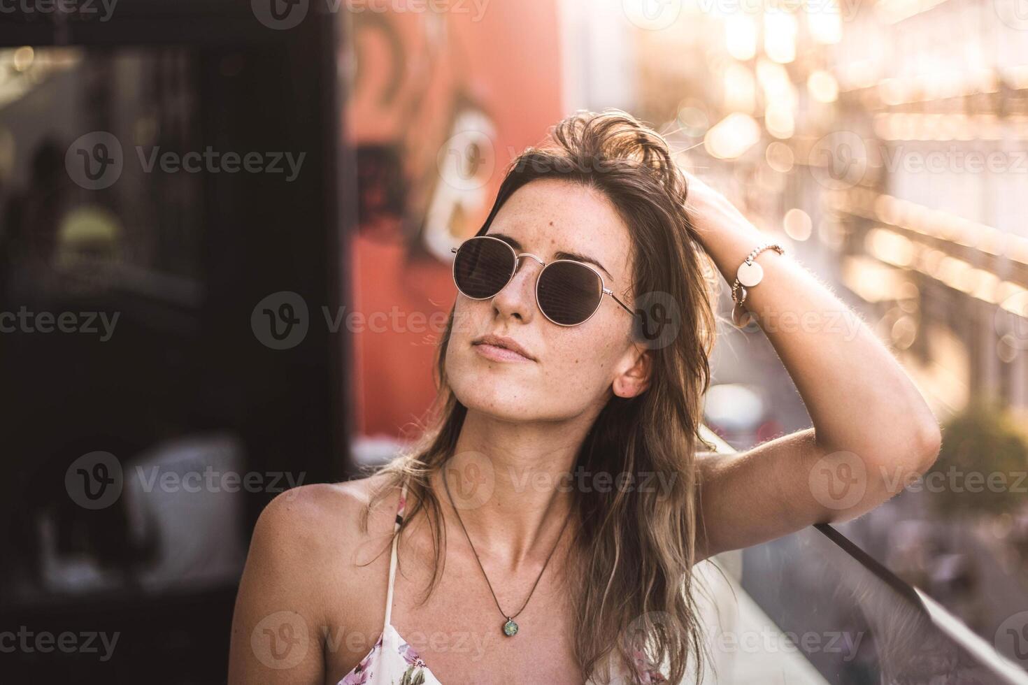 A woman wearing sunglasses and a floral top. photo