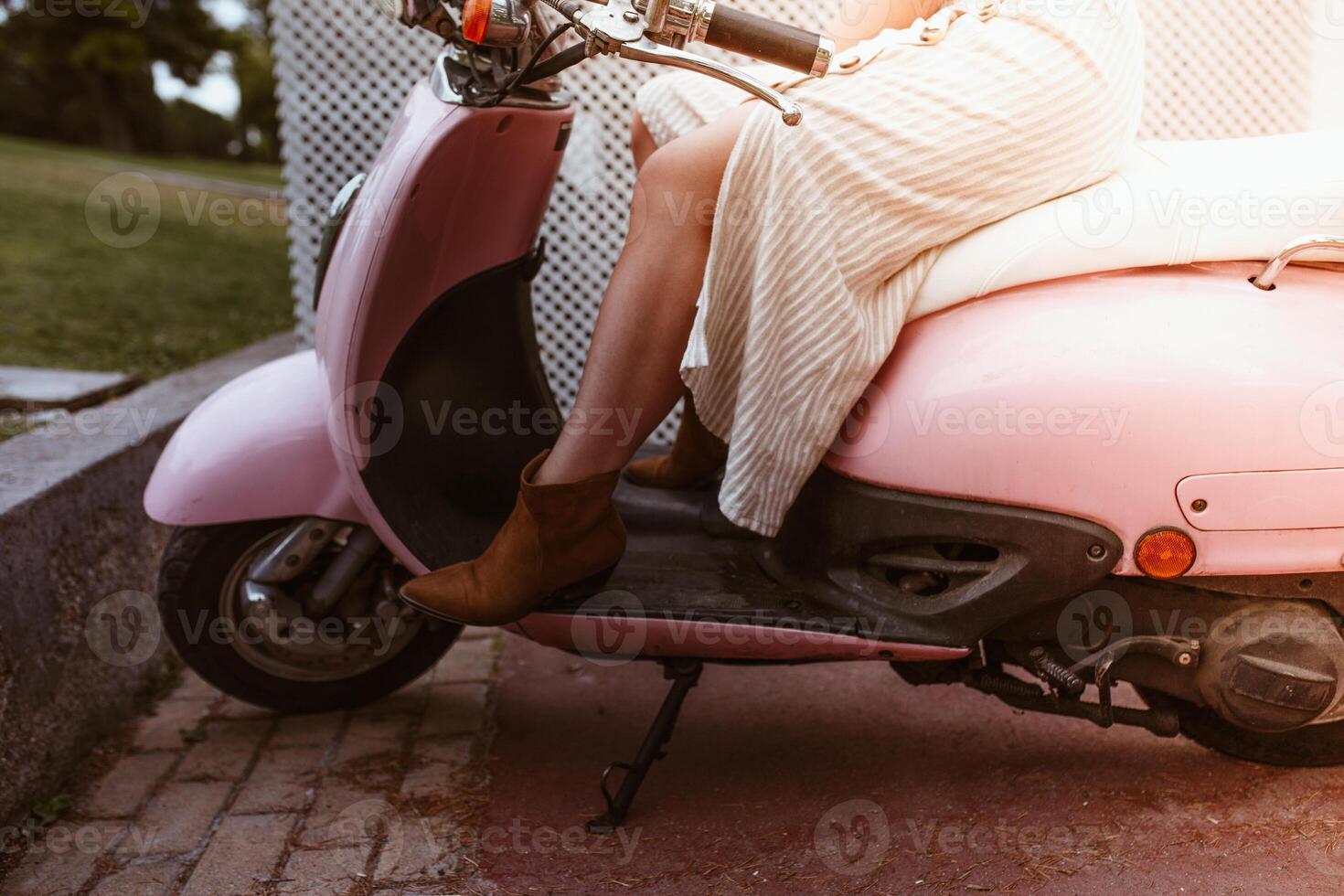 A woman in a white dress sitting on a pink scooter photo
