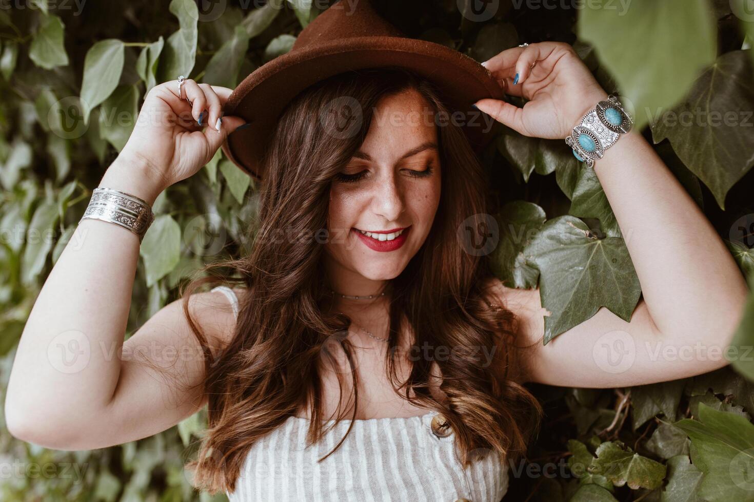 A woman wearing a hat and holding her hair photo