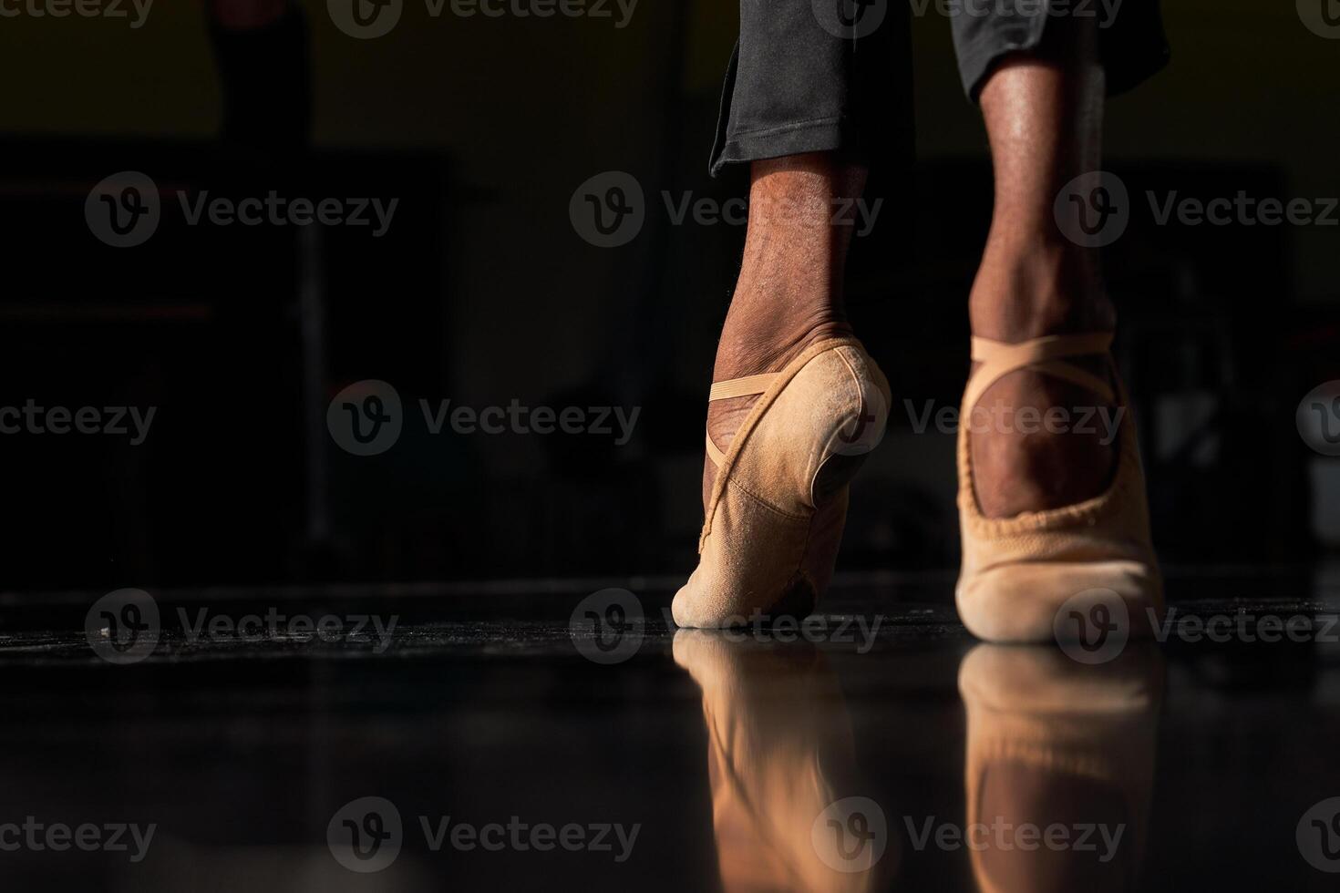 A person's feet in ballet shoes on a black floor photo