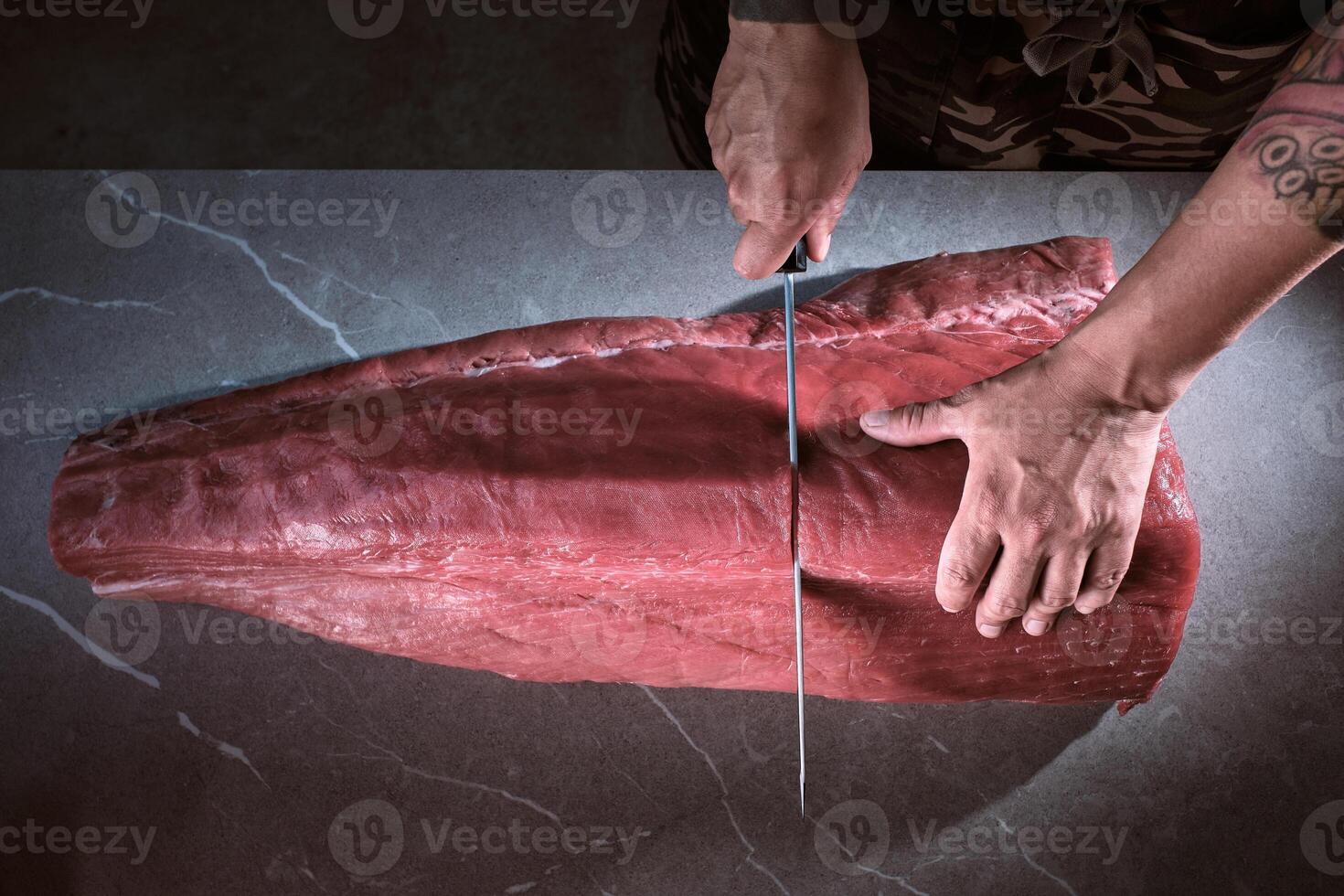 A person cutting a piece of meat on a counter photo