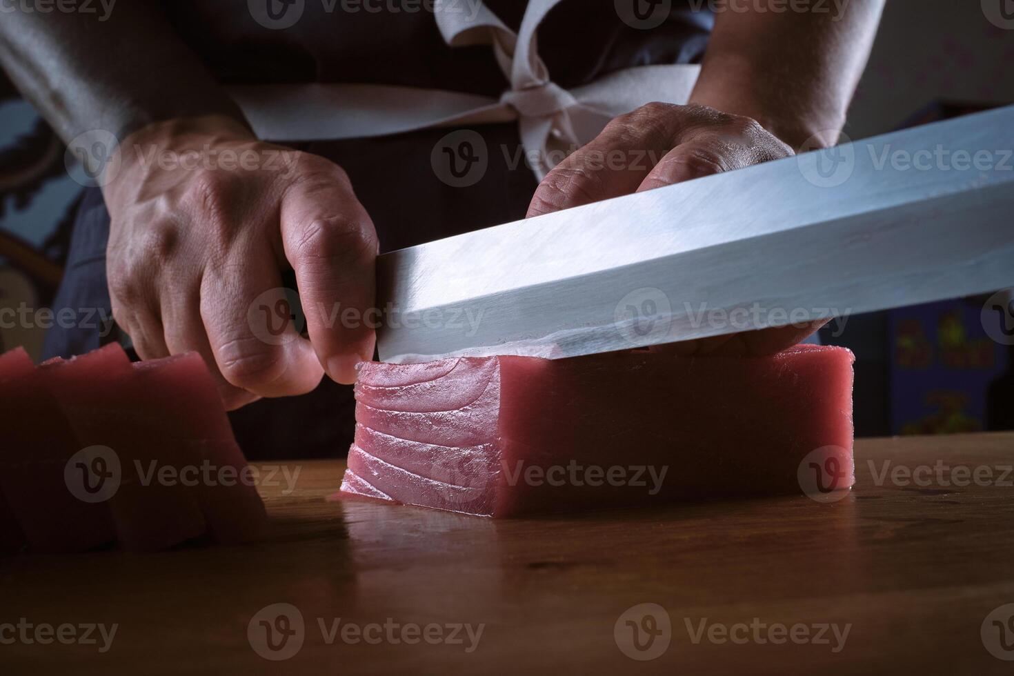 A person cutting up a piece of raw meat with a sharp knife photo