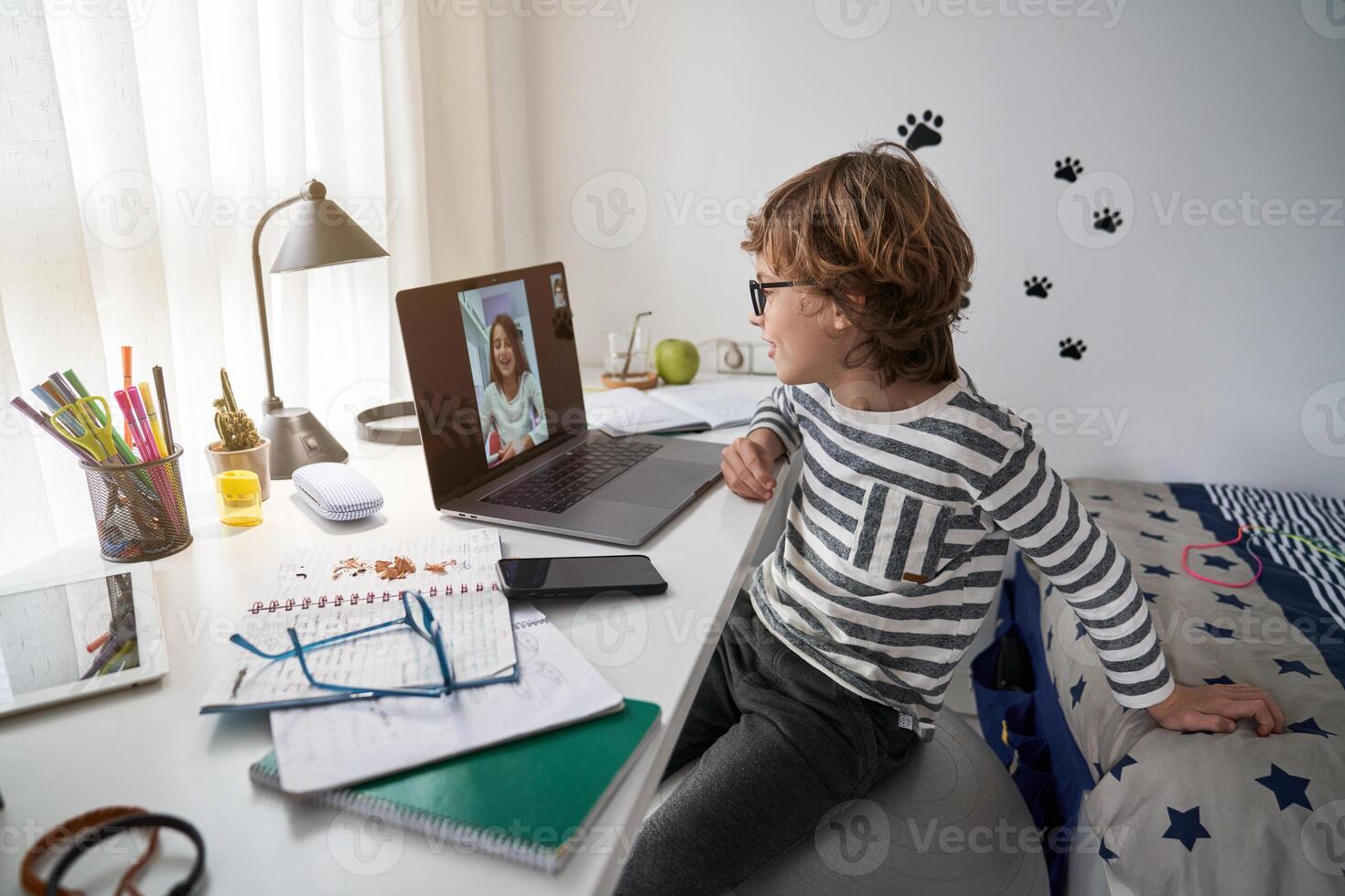 A young boy sitting at a desk with a laptop photo