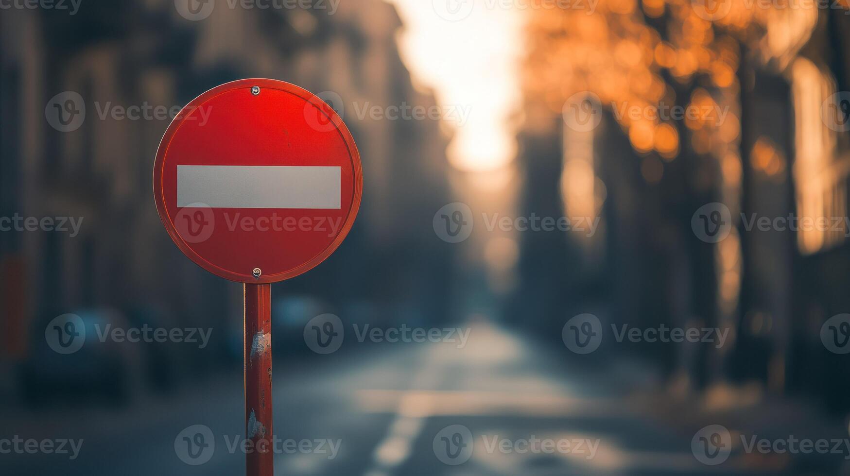 A red no entry sign stands on an empty street at sunset. photo