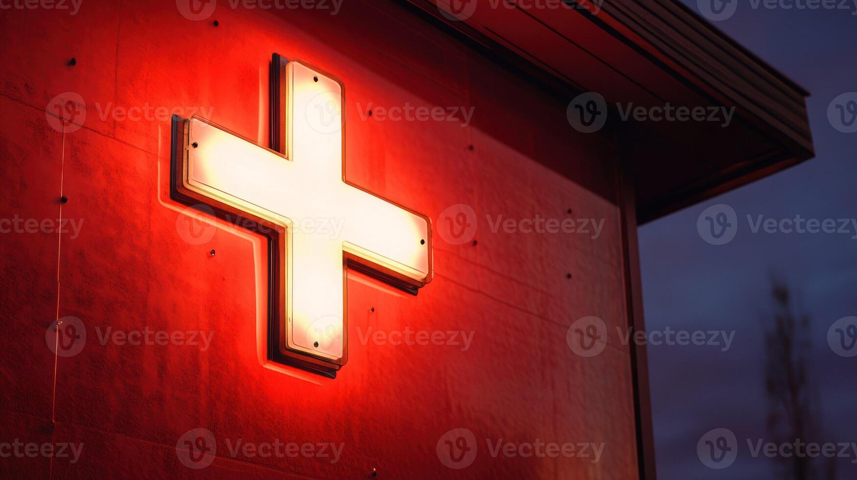 Illuminated red cross sign on a building at night. photo