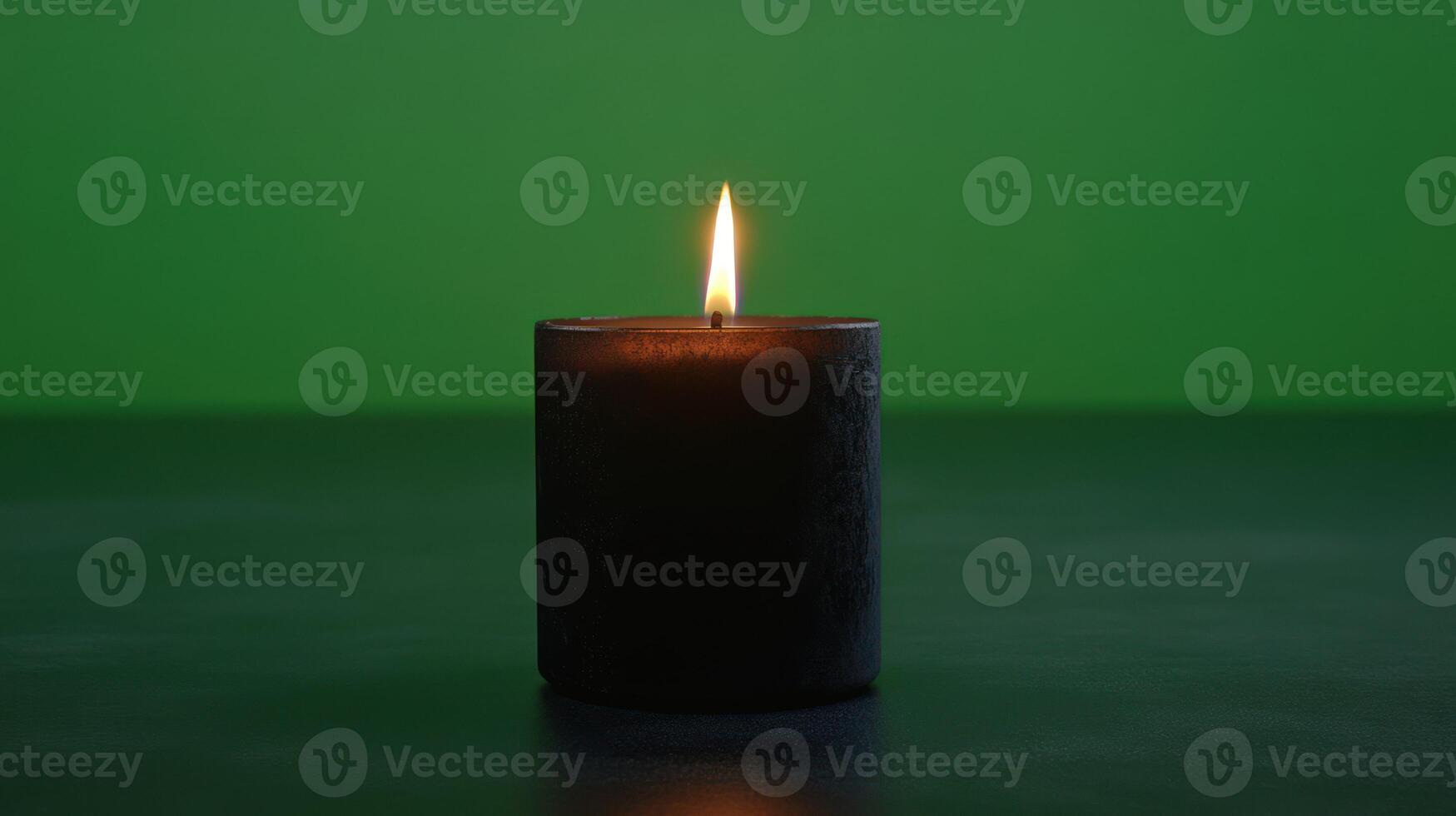 A glowing black candle against a green background creates a calming ambiance. photo