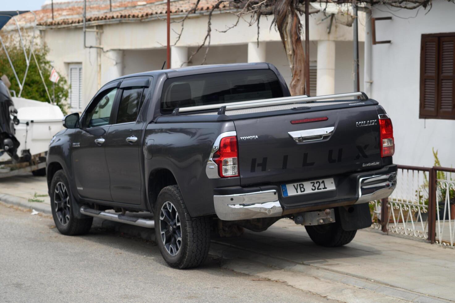 Gaziveren Cyprus -17.03.2025 Toyota Stylish black pickup truck parked beside a charming coastal road near fishing boats on a sunny afternoon photo