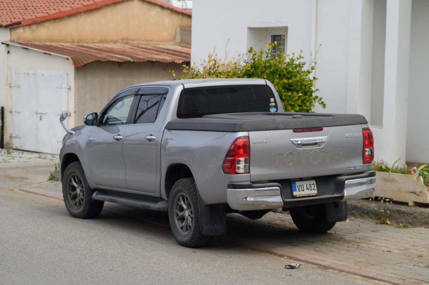 Gaziveren Cyprus -17.03.2025 Silver pickup truck parked on a quiet street under a cloudy sky in a small town setting photo