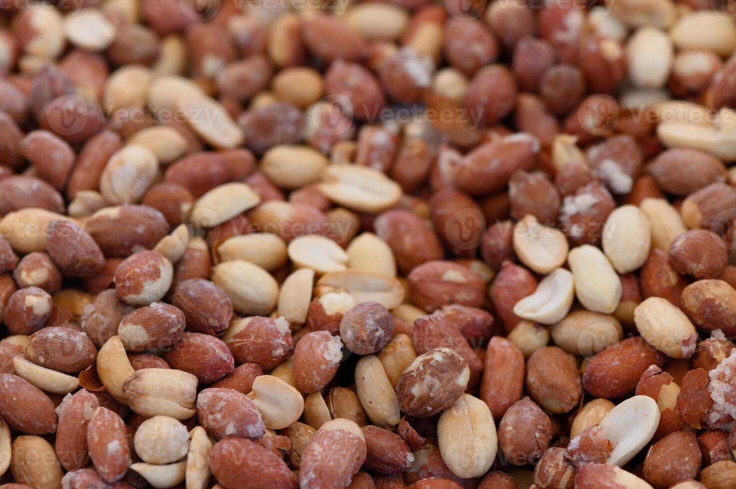 Varied textures and colors of peanuts spread across a market table in a vibrant setting photo