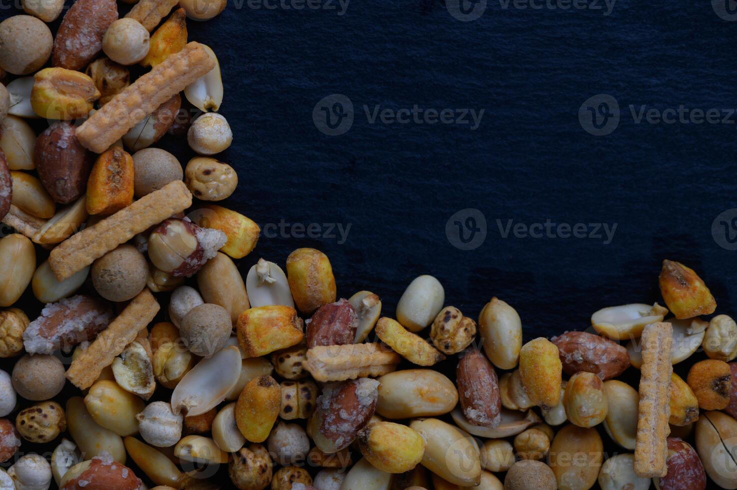 Colorful assortment of mixed nuts and snacks arranged artistically on a dark background, showcasing their textures and shapes photo