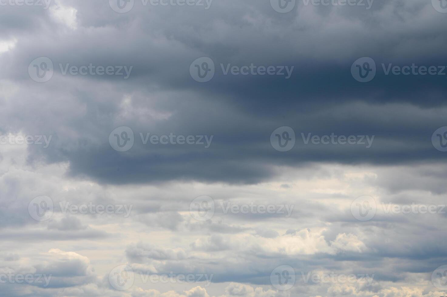 Dramatic clouds gather over a tranquil landscape at dusk, hinting at an approaching storm and the promise of rain photo
