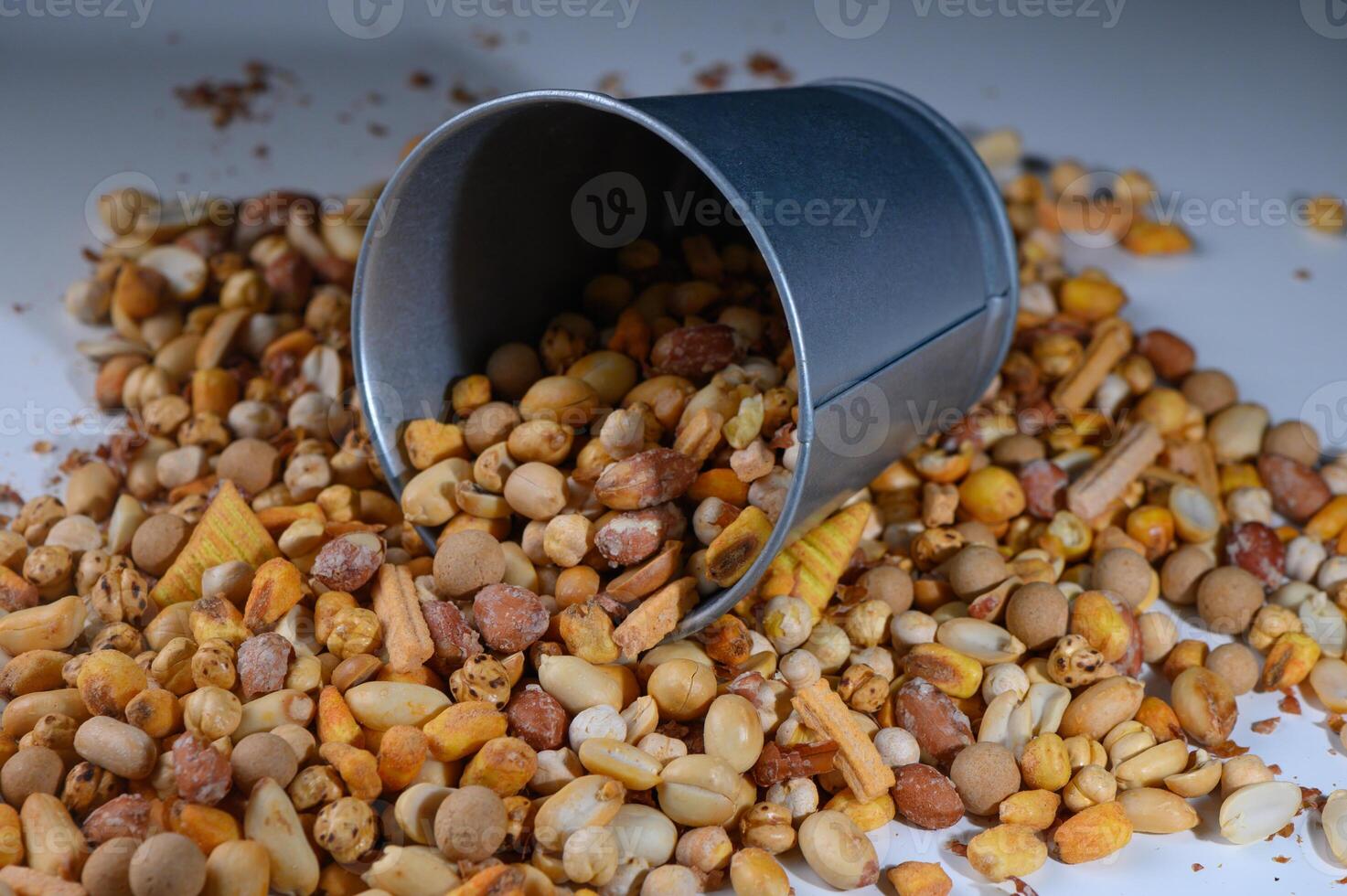 Colorful assortment of nuts spills from tin container creating a vibrant snack display on a bright surface photo