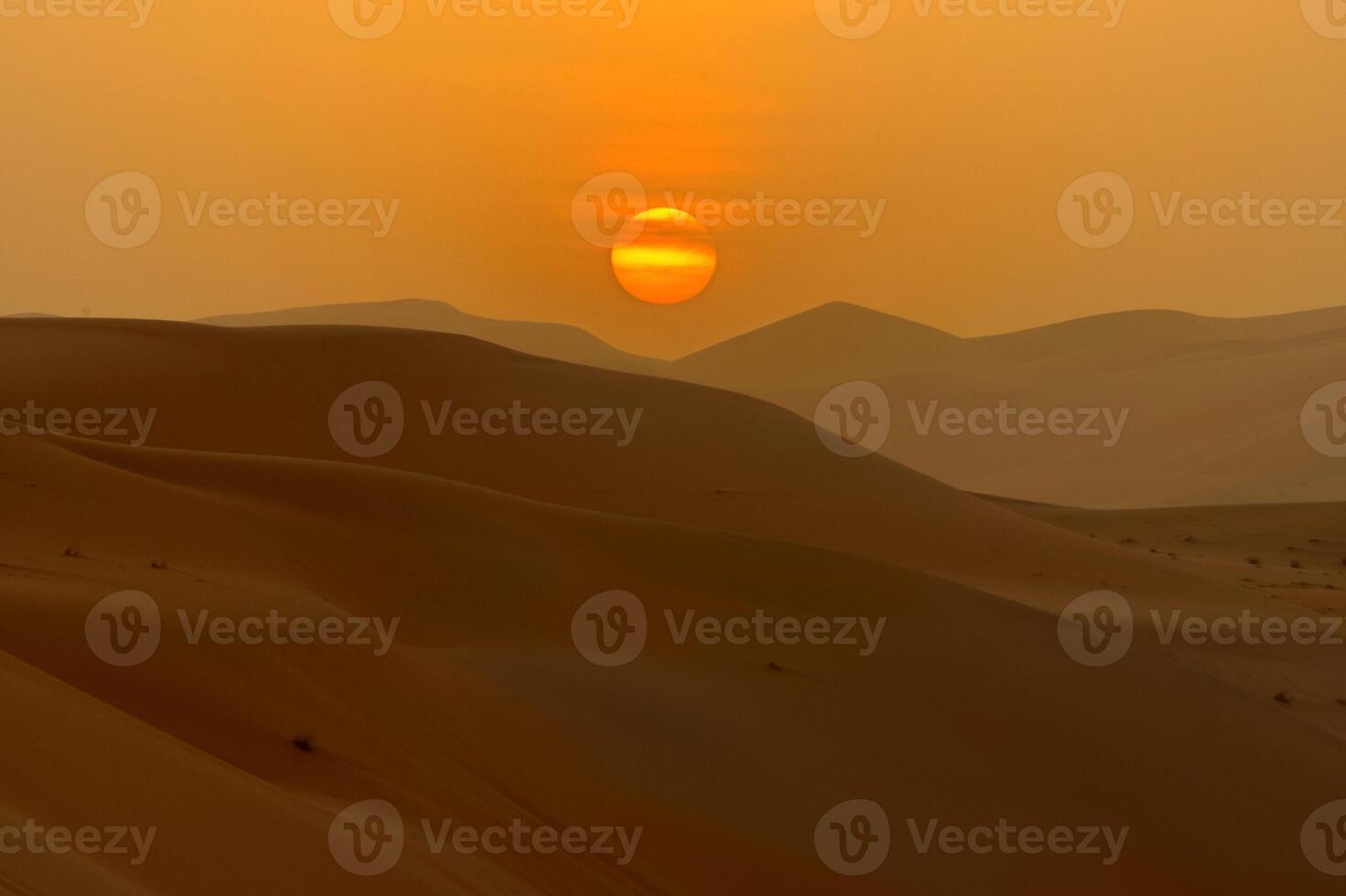 A desert scene with a sun setting over the sand photo