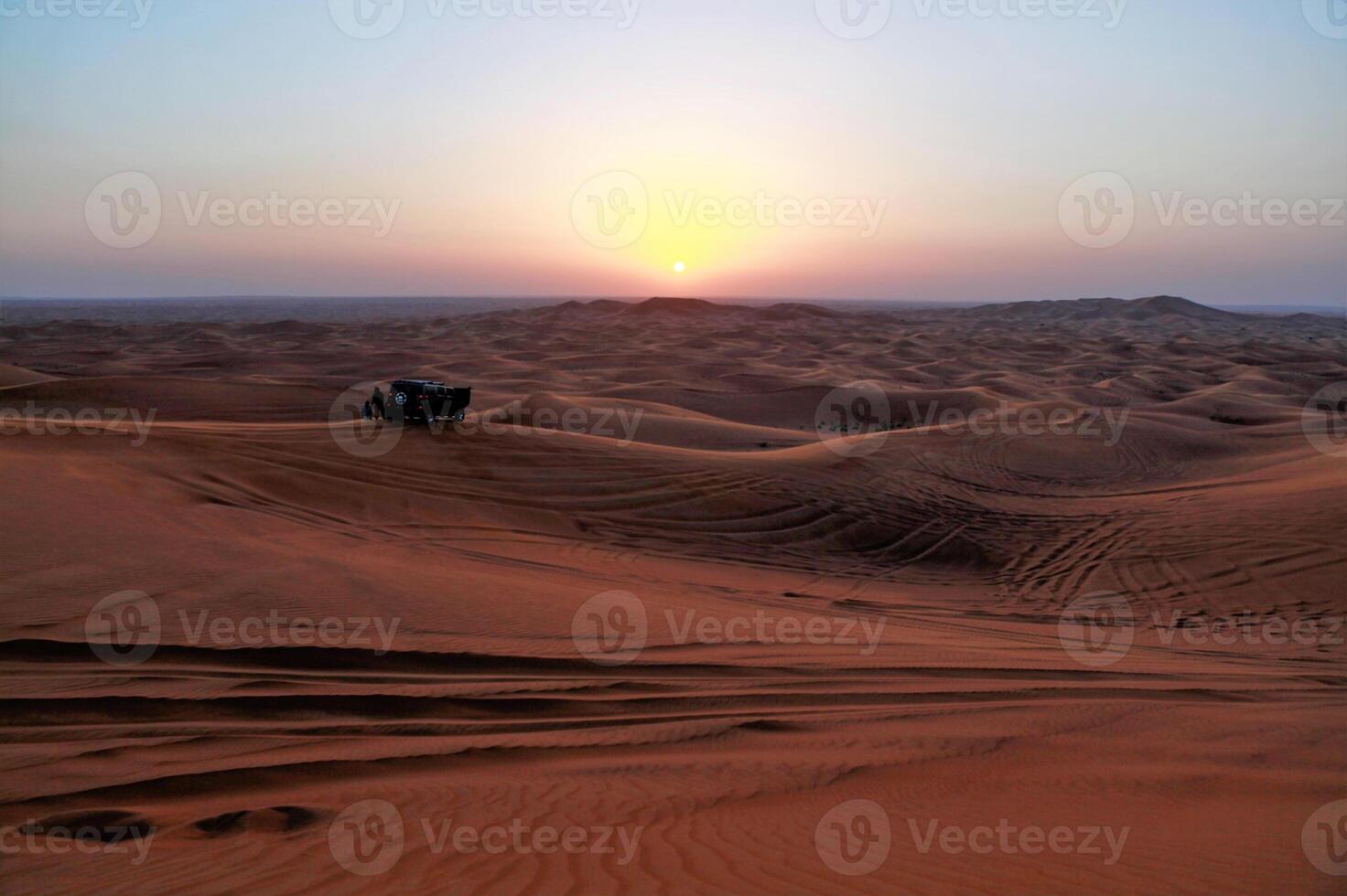 A jeep driving through the desert at sunset photo