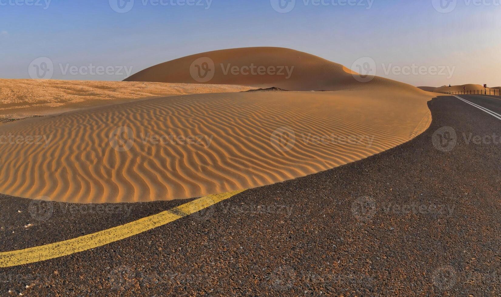 A desert road with sand dunes in the background photo