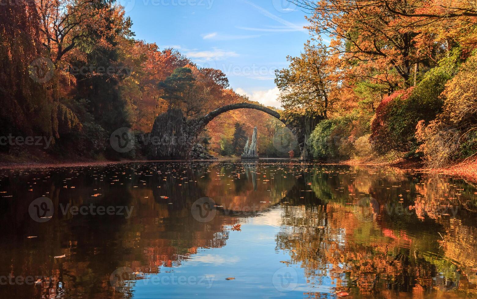 A bridge over a river surrounded by trees in the fall photo