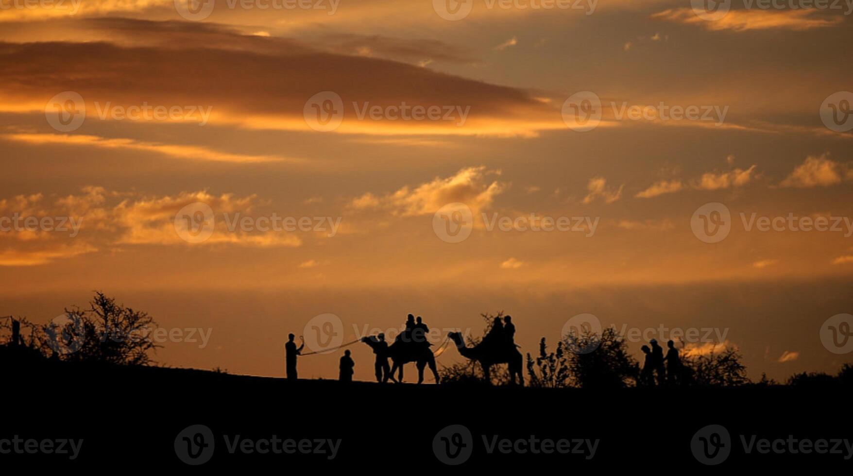 Three people on camels are silhouetted against a sunset photo
