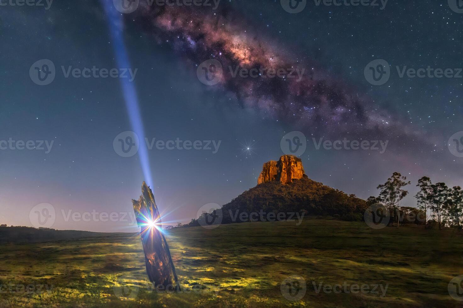 A light shines on a tree stump in the middle of a field photo