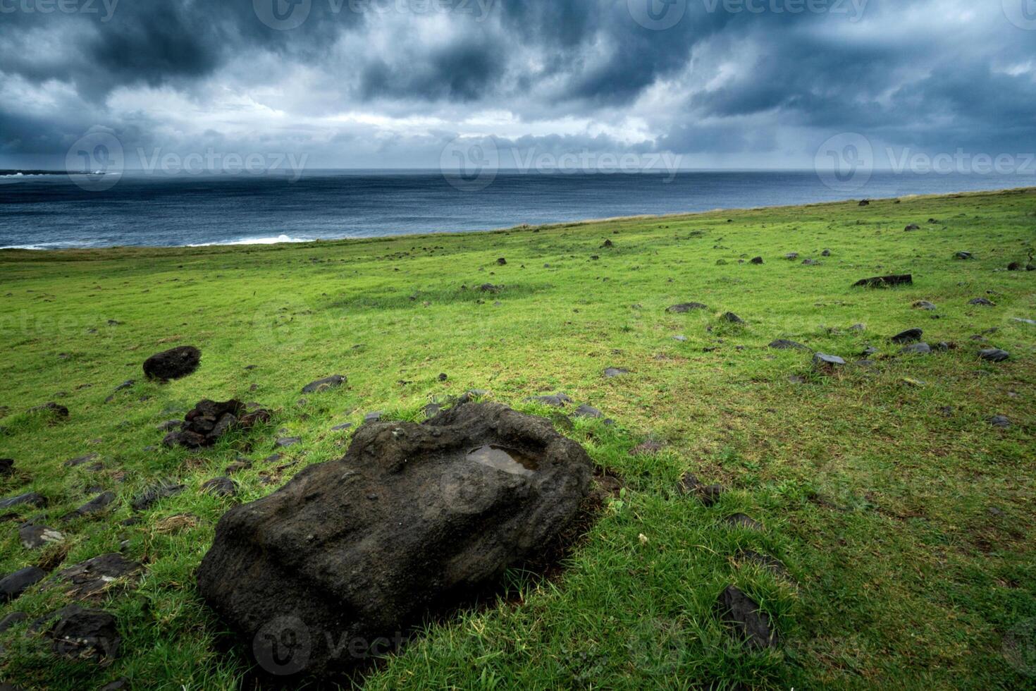 A large rock sits in the grass on a green field photo