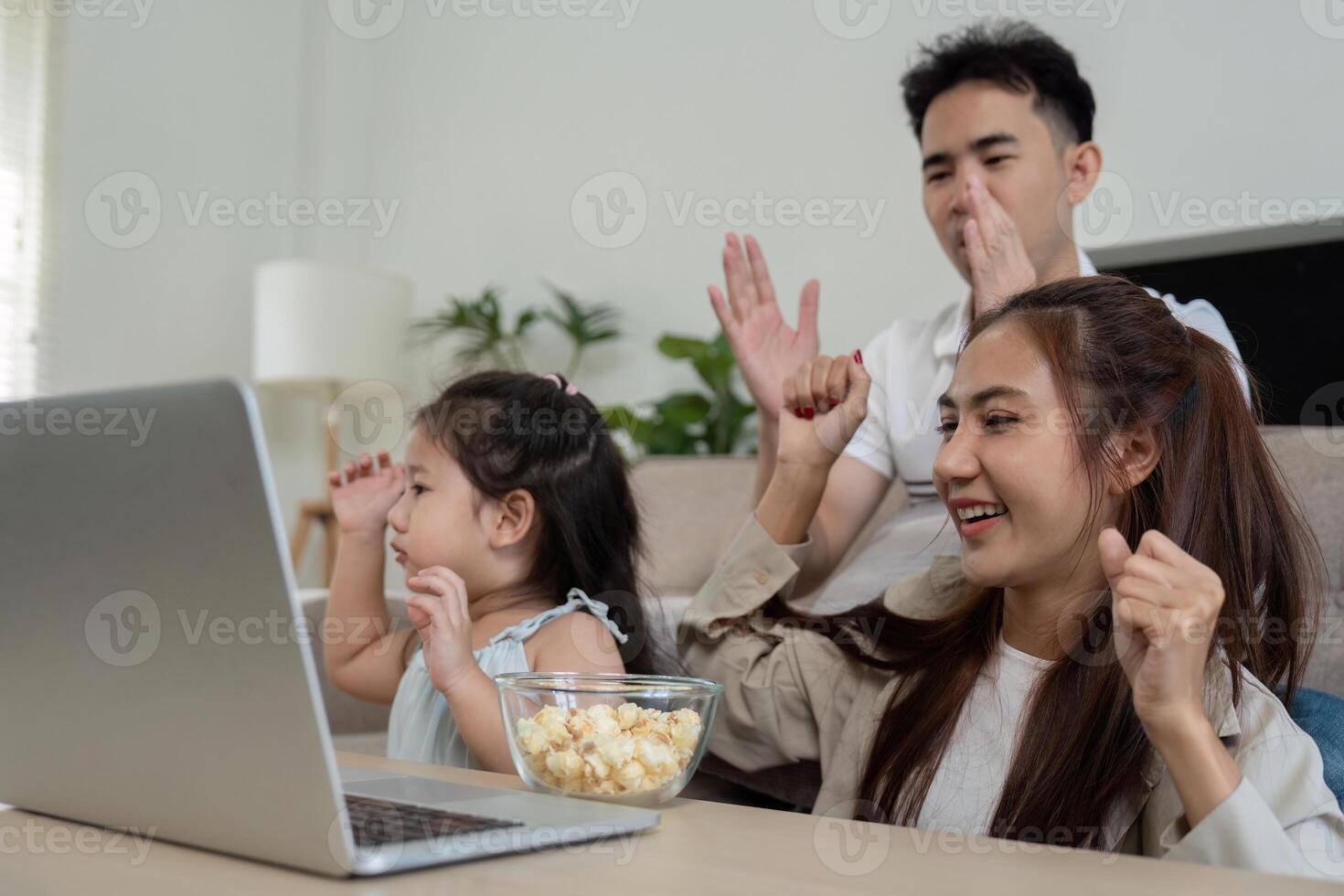 Joyful Family Moments and Movie Time. A fun family scene where the parents and daughter cheer while enjoying a film together. photo