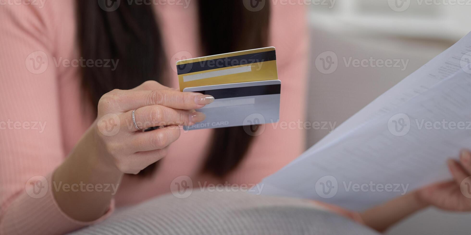 Credit Management and Finance Strategy. Close-up of a woman holding multiple credit cards and reviewing paperwork as part of her financial strategy. photo