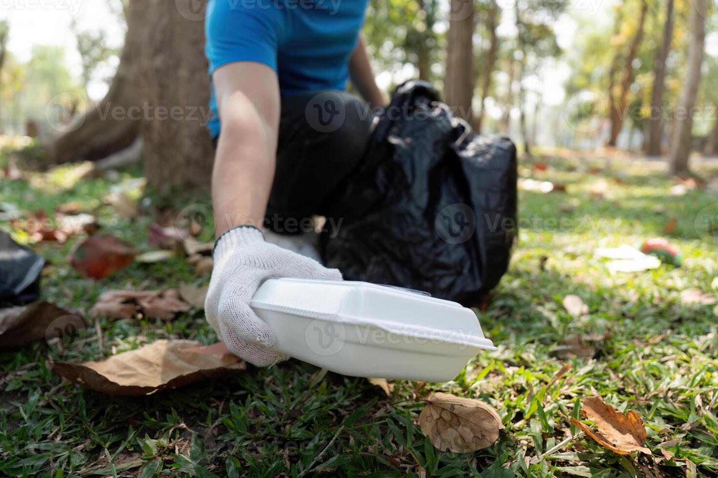 Sustainability and Volunteerism. An individual picking up litter in a park for environmental clean-up. photo