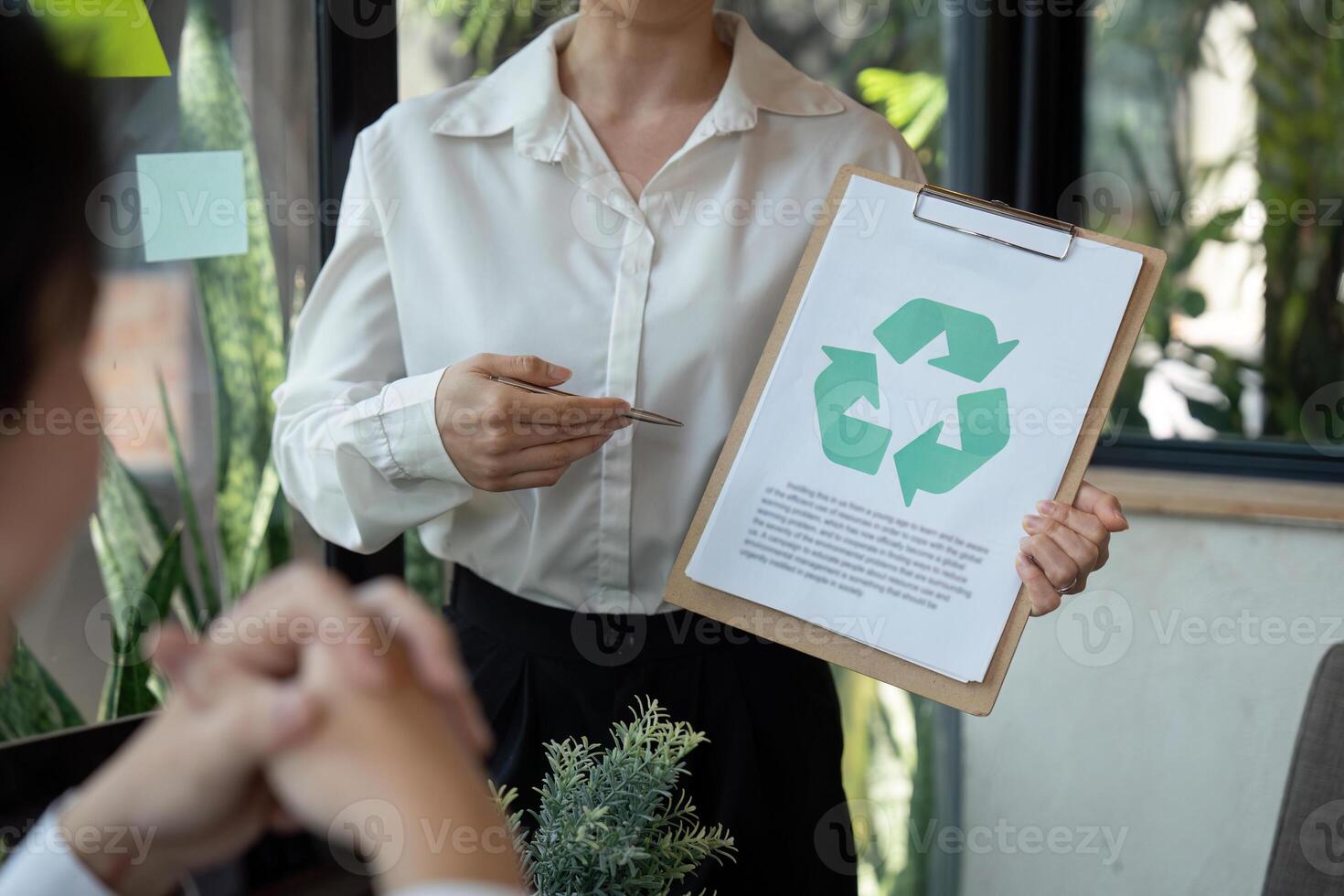 Sustainable Practices and Symbolic Actions. A professional discussing recycling initiatives while holding an informational sheet in a meeting. photo