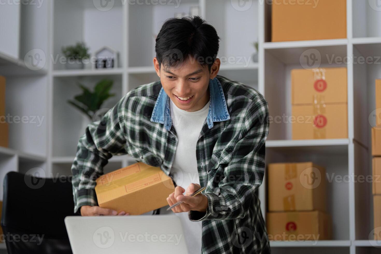 Entrepreneurship and Online Sales. A young man packaging products for e-commerce with a smile. photo