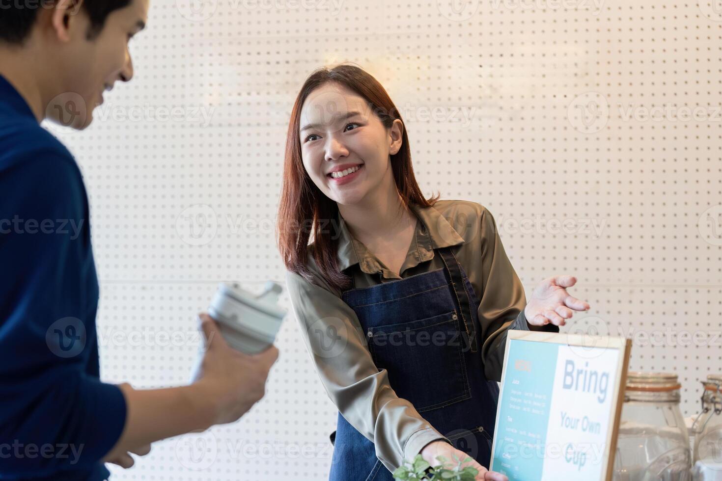 Sustainability and Customer Engagement. A barista encourages customers to bring their own cups for an eco-friendly experience. photo